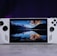 A handheld gaming console with a central screen displaying a scenic wallpaper of mountains and a lake, flanked by controller buttons and joysticks on both sides. The lighting around is dim, with purplish hues in the background, creating a modern and elegant atmosphere.
